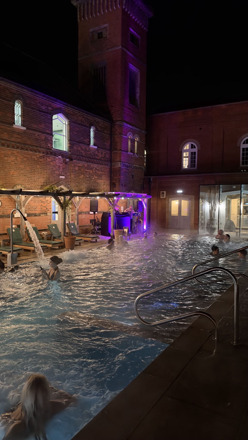 Outdoor spa pool and red-brick buildings lit at twilight